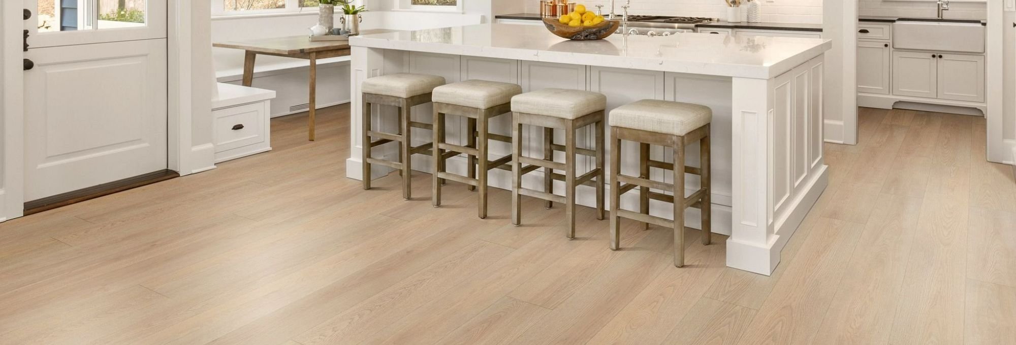 White kitchen island and white chairs with white kitchen cabinets and brown hardwood flooring from Butler Floors in the Austin, TX area